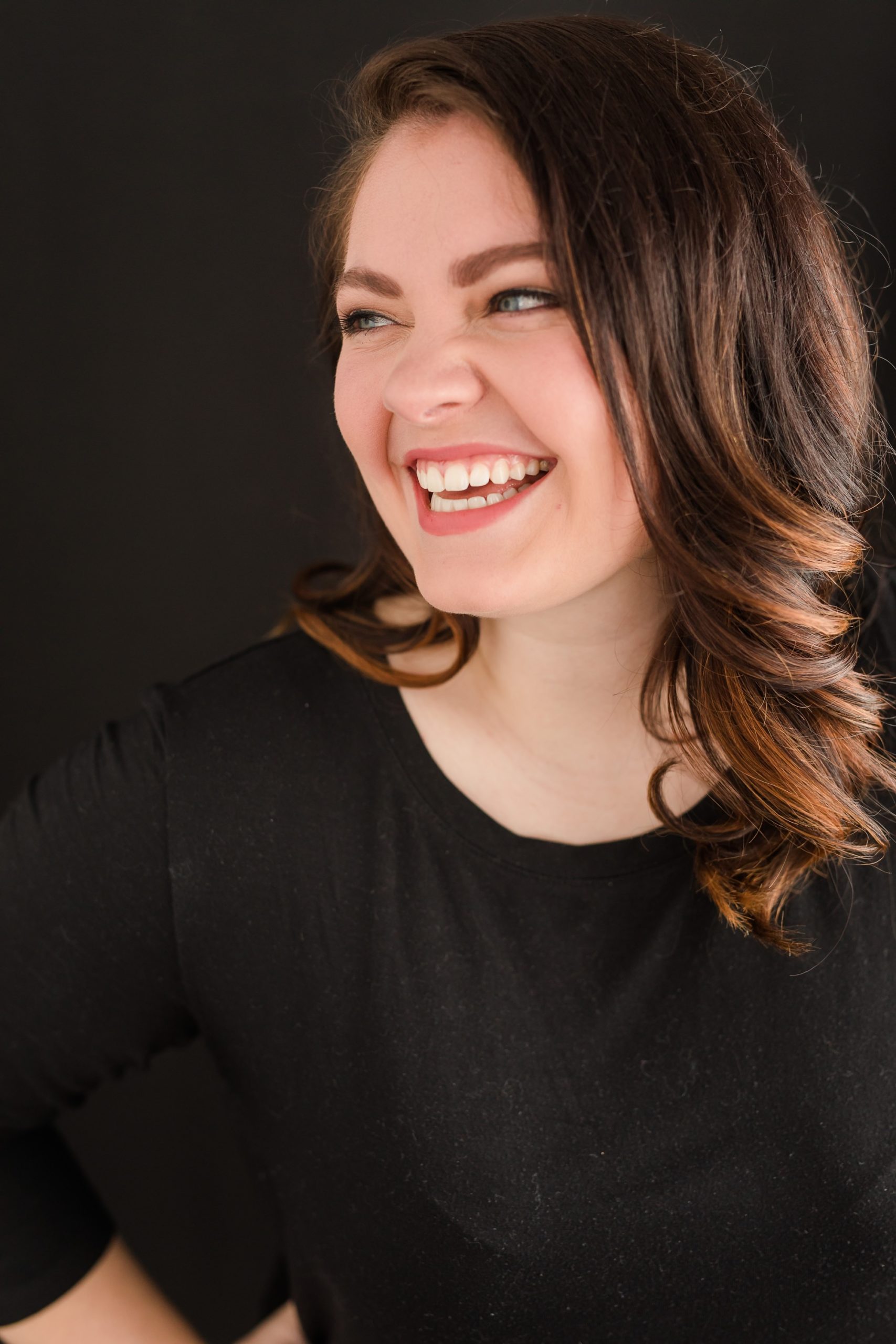 Business headshot, laughing off to the side on a black backdrop