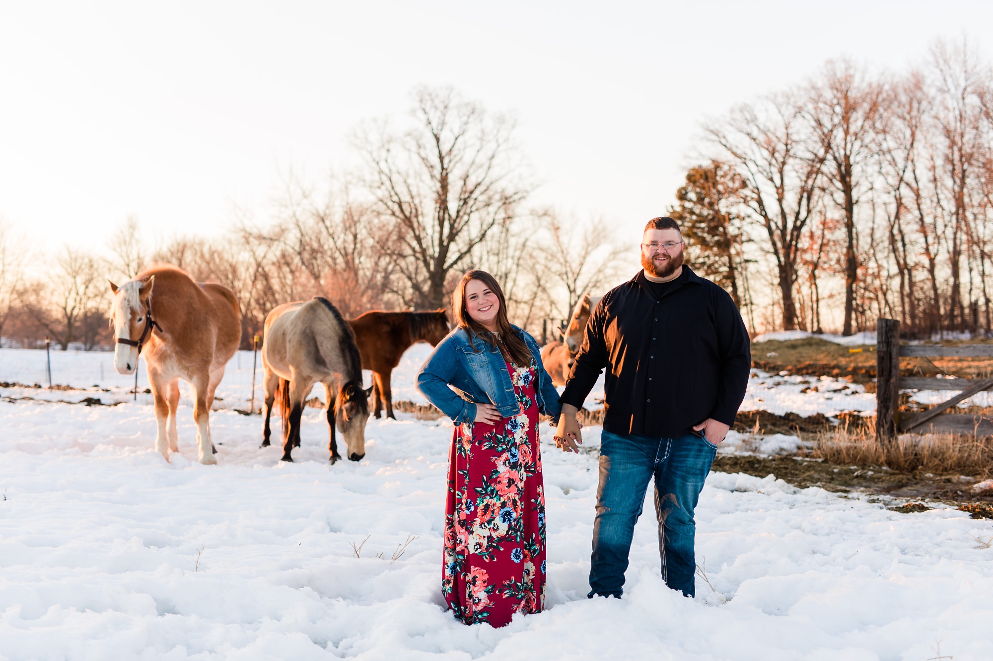 Couple standing in front of horses in the Minnesota Winter Snow