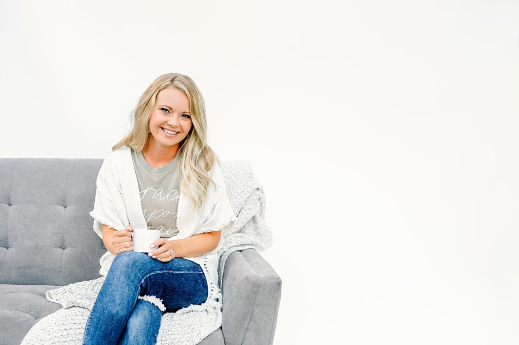 podcaster sitting on a grey couch holding a coffee mug branding portrait
