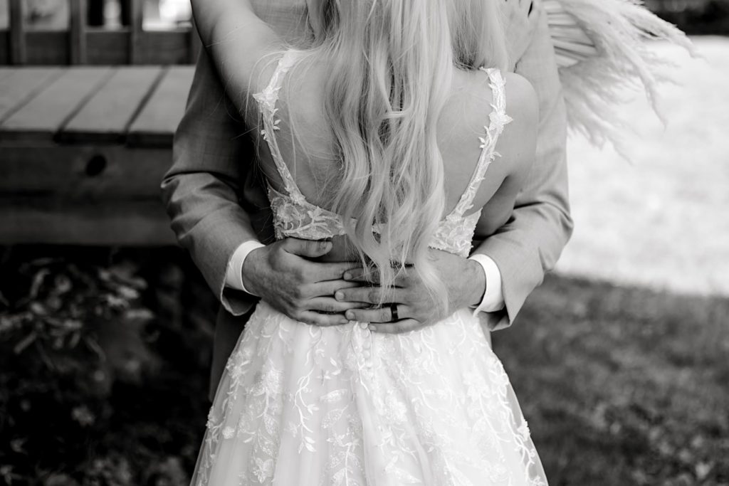 black and white photo of groom's hands holding bride's waist 