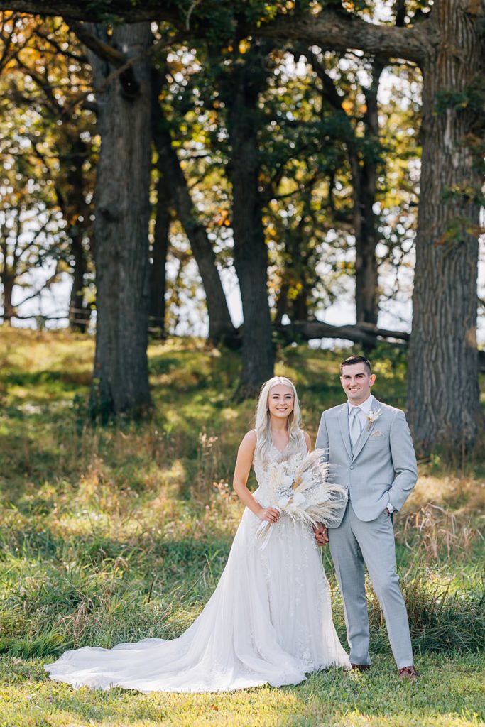 Bride and groom posing in front of oak trees at the Hitching Post Minnesota