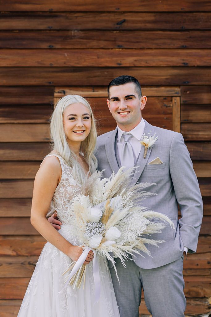 Bride and Groom portrait, looking at camera in front of barn wood building