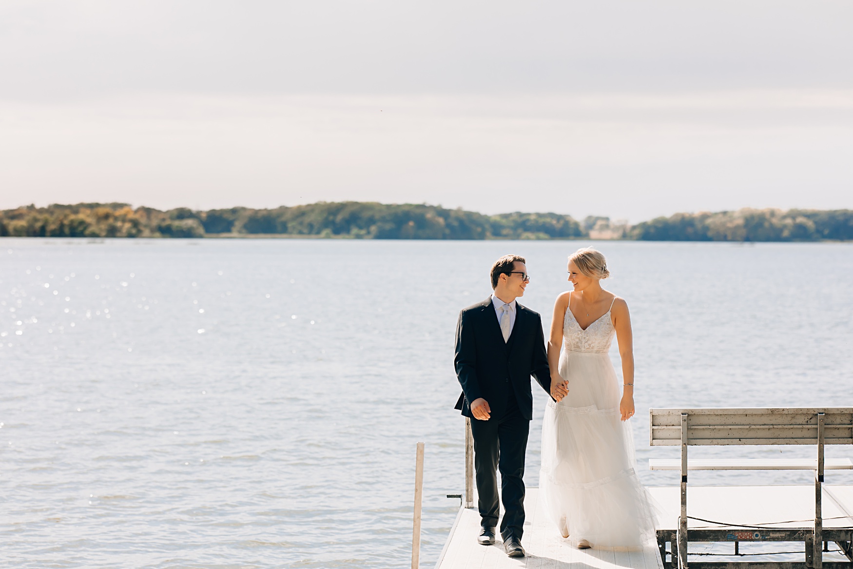 Willmar, MN Stonewall Farms Wedding | Bride and groom walking, holding hands on a dock