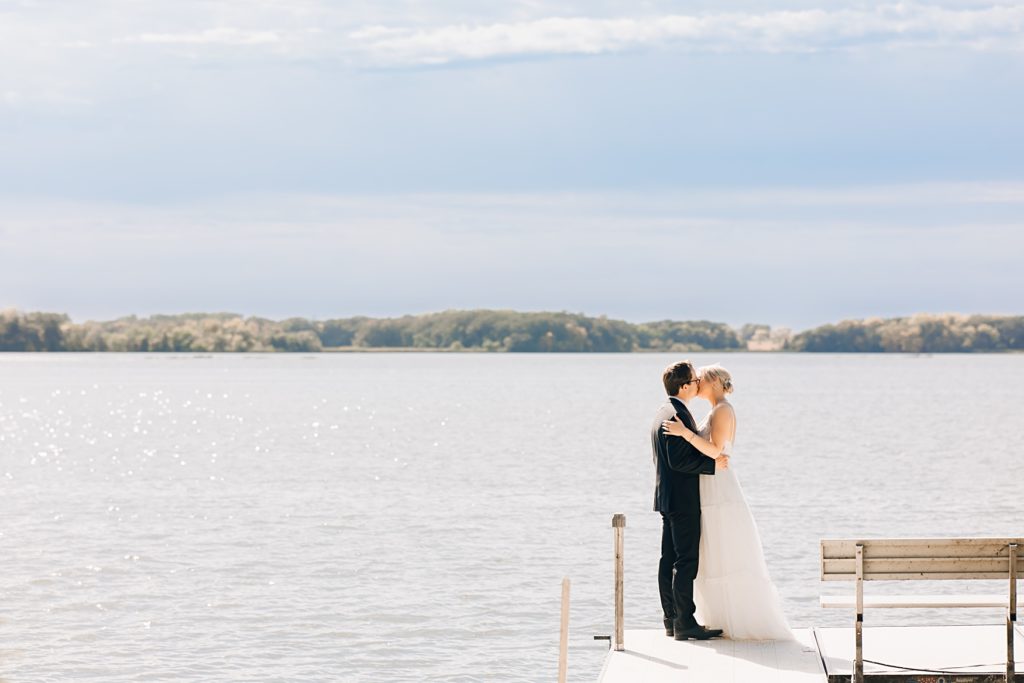 bride and groom kissing on dock at Willmar, MN Stonewall Farms Wedding