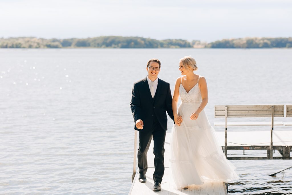 bride and groom walking down dock at Willmar, MN Stonewall Farms Wedding