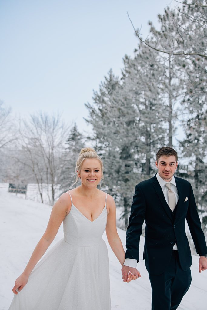 Bride and groom walking in front of pine trees