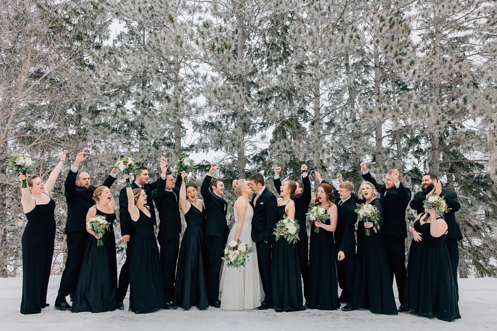 Bridal party posed in the snow in front of pine trees at the Timbers Event Center in Staples, MN