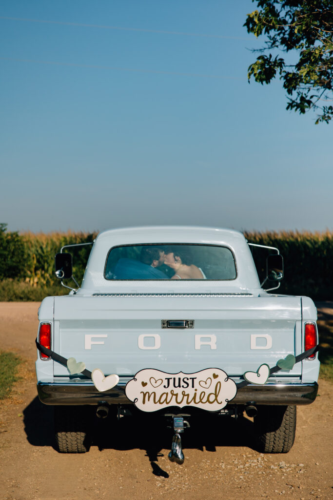 bride and groom driving away in 1966 ford pickup