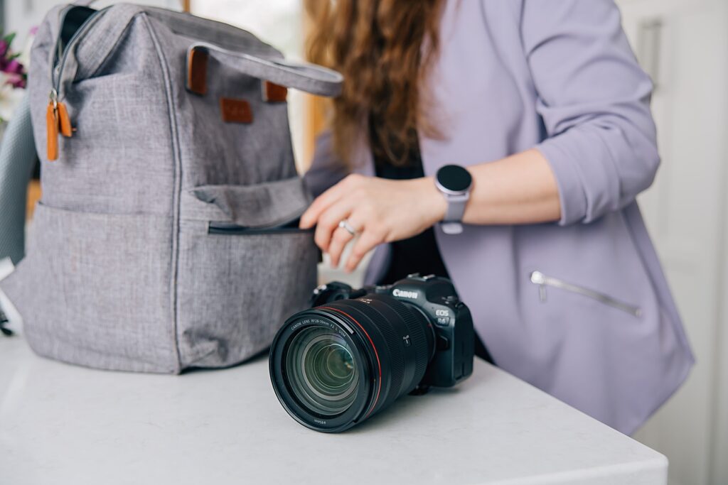 Business owner packing her camera while wearing an aspirational outfit to her brand photography session