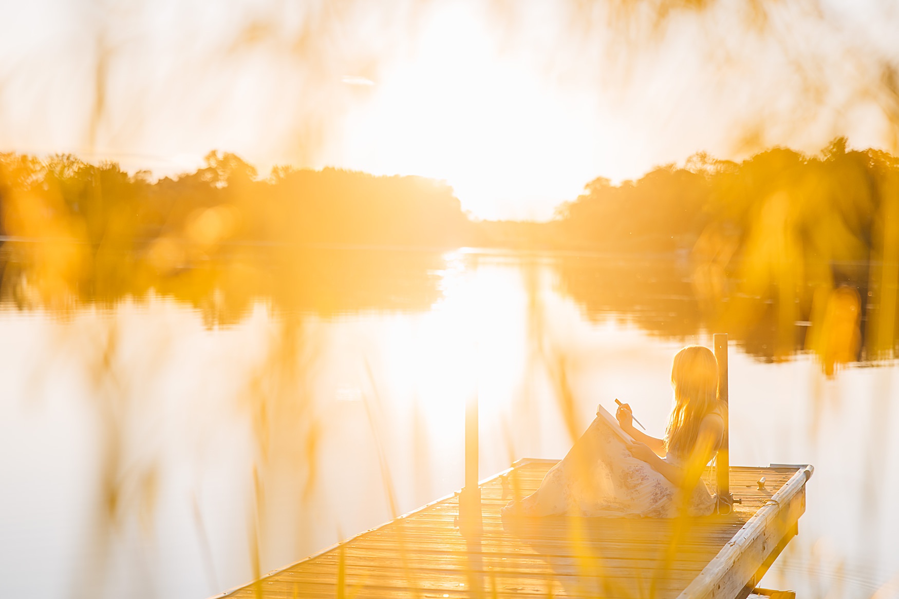 Senior picture ideas: sitting on a dock painting at sunset