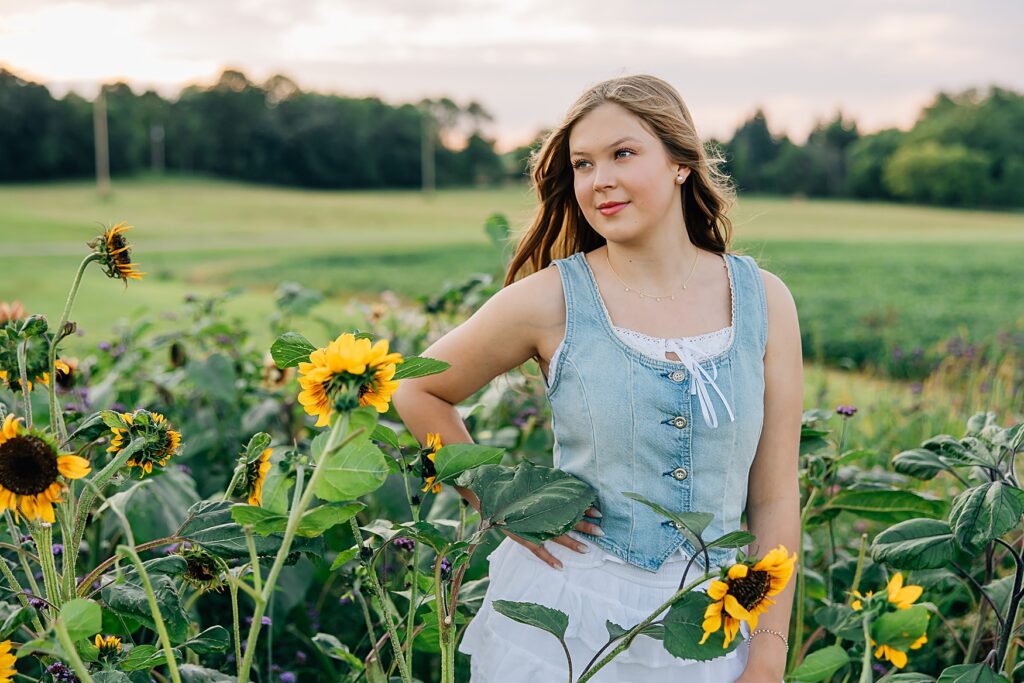 senior girl standing in field of sunflowers