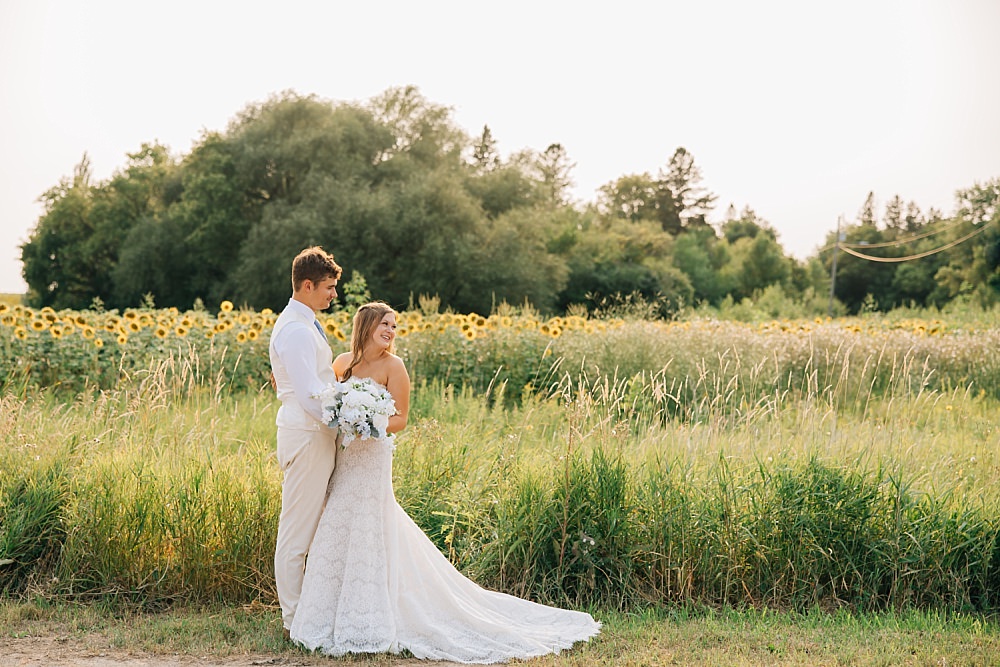 A wedding couple next to a sunflower field at golden hour